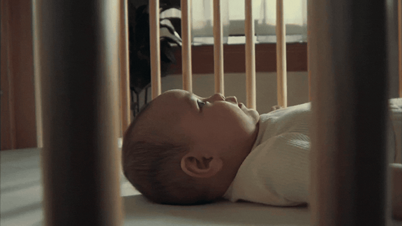 A baby looks at a mobile of sports balls for Canadian Tire